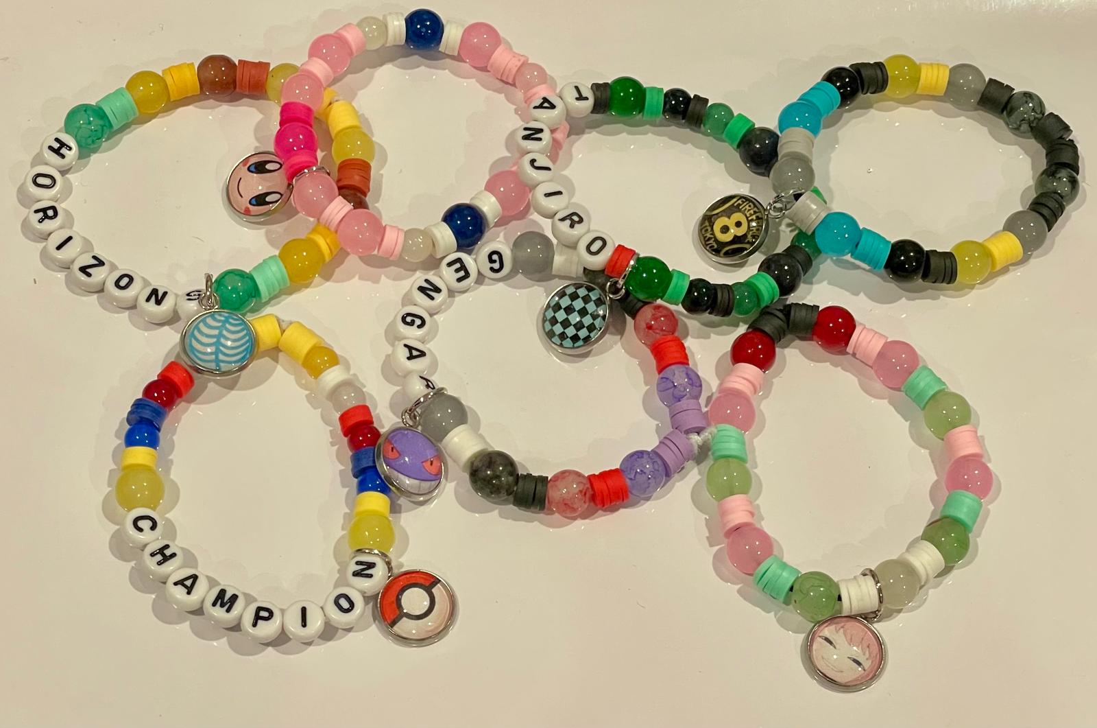 Colorful beaded bracelets with various charms from anime and video games on a white background