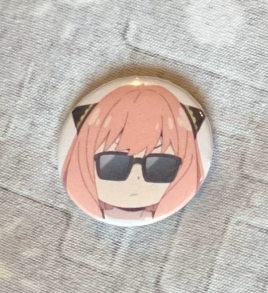 Button badge with an anime character wearing sunglasses on a textured surface