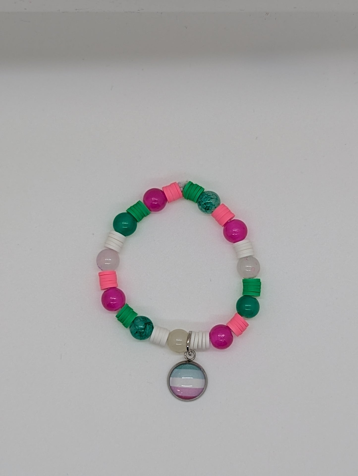Colorful beaded bracelet with a circular charm on a white background