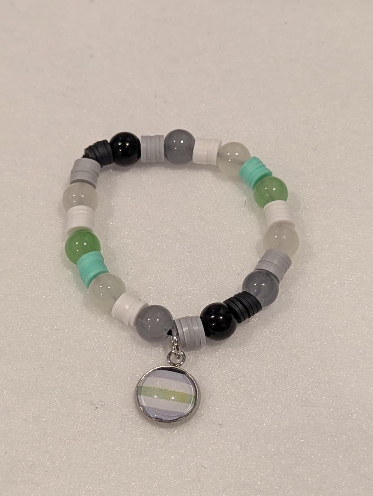 Beaded bracelet with a circular charm on a light gray background
