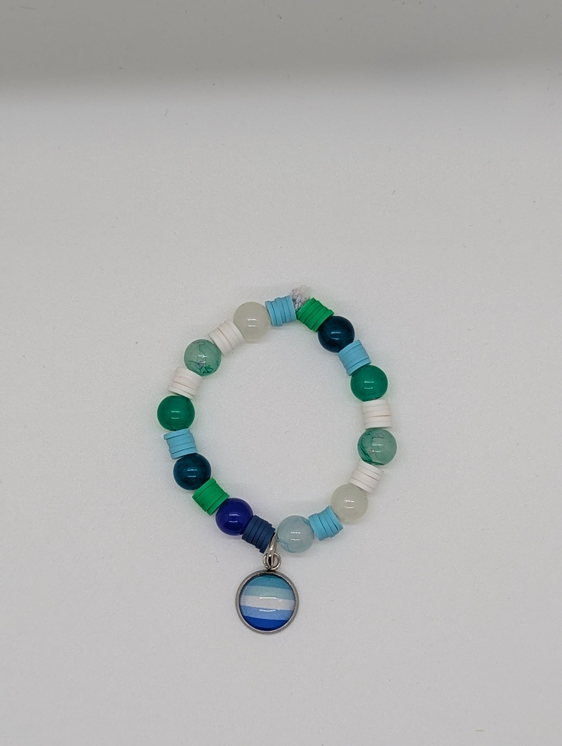 Multicolored beaded bracelet with a circular charm on a white background