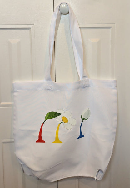 White tote bag with colorful flower design hanging on a white door.