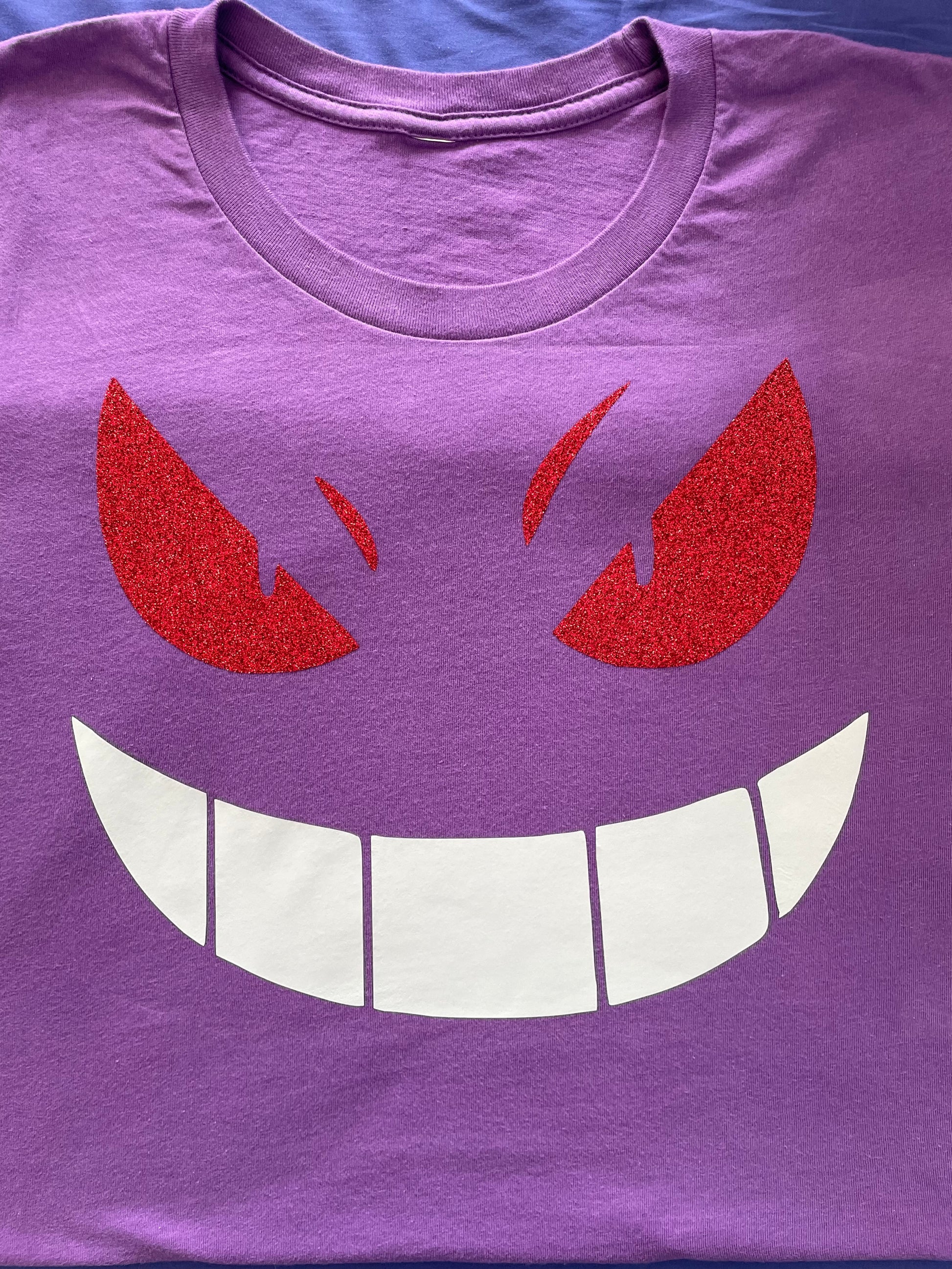 Gengar pokemon face printed on a purple t-shirt.