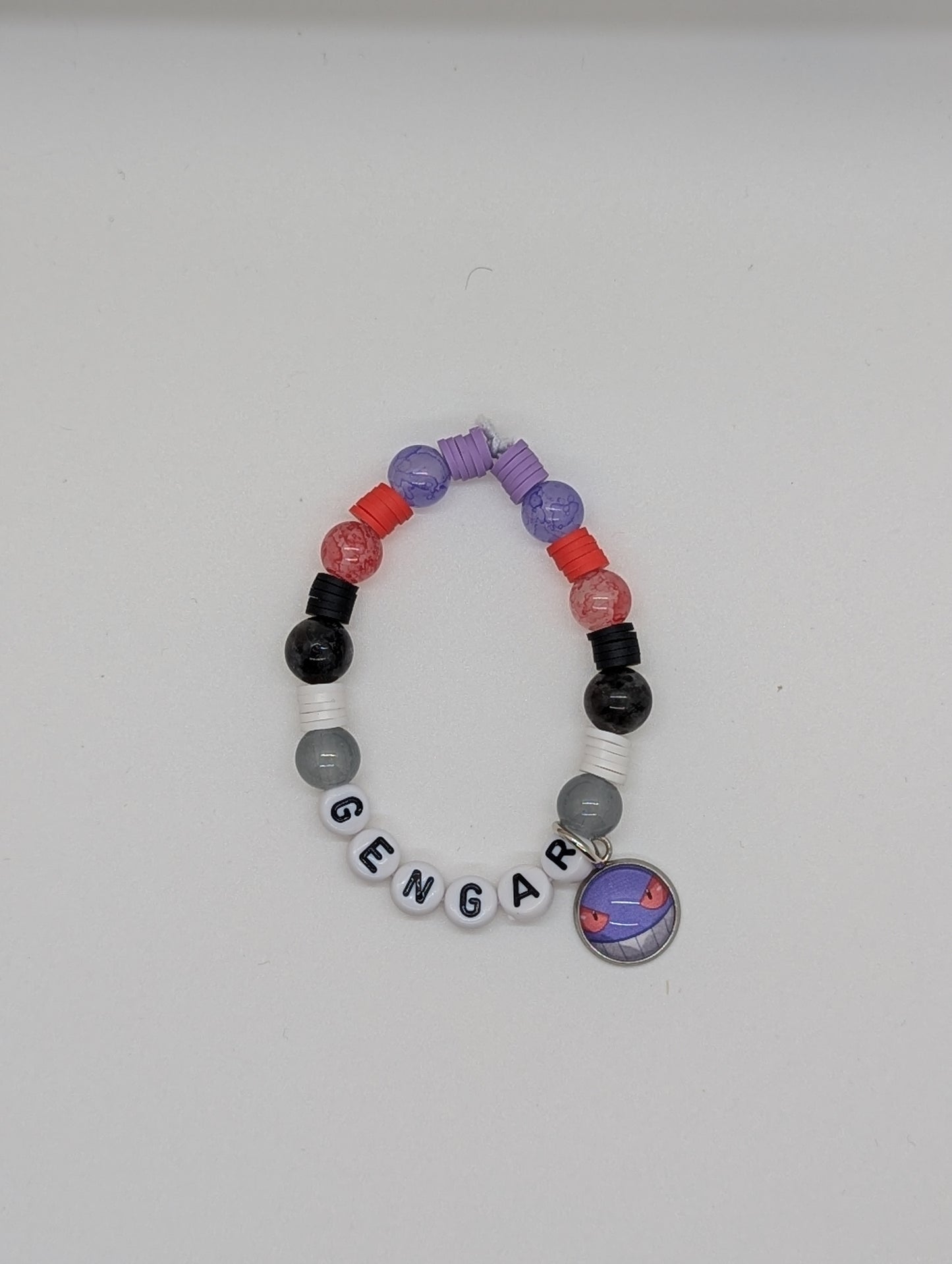 Colorful beaded bracelet with a 'Gengar' charm on a white background