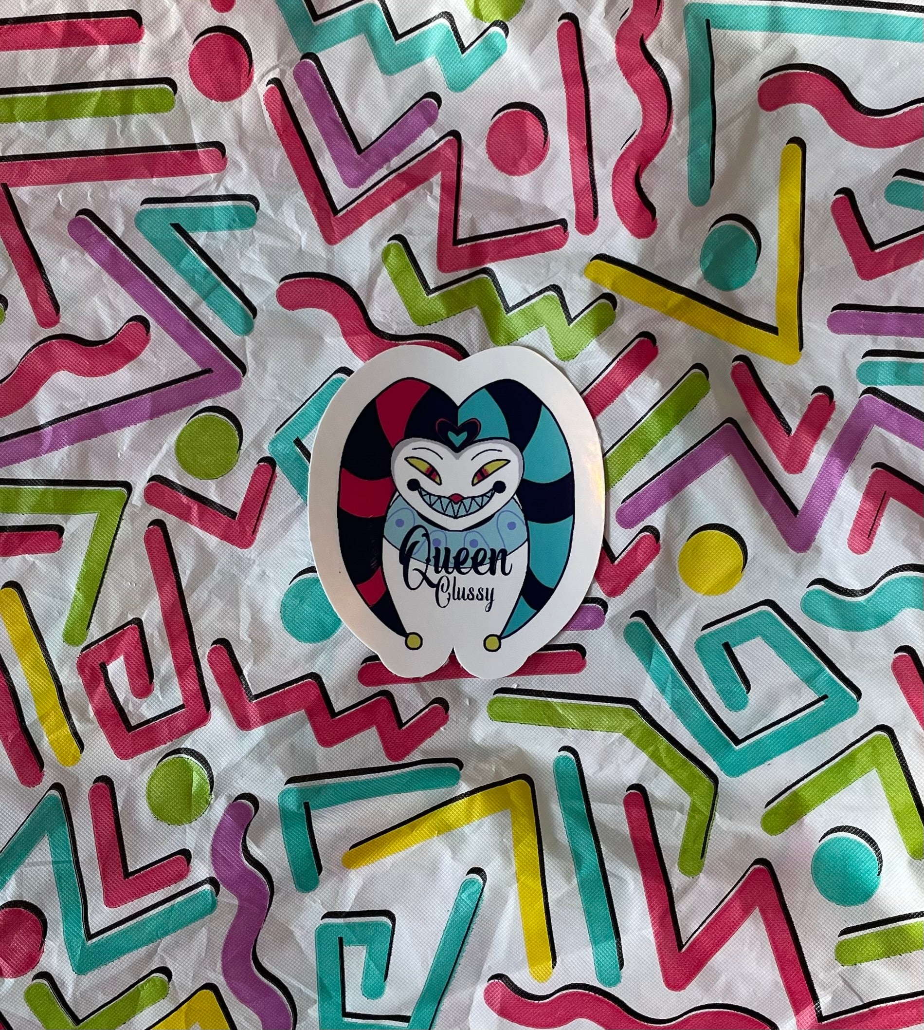 Colorful geometric pattern with a sticker featuring a cat and 'Queen Classy' text.