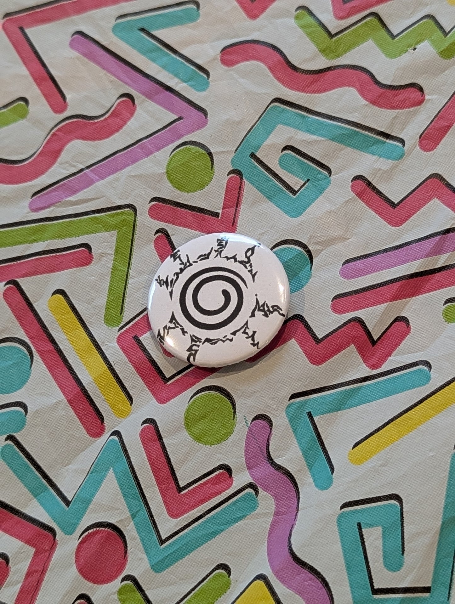 Button with a spiral design on a colorful geometric patterned background