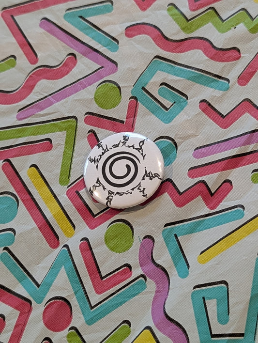 Button with a spiral design on a colorful geometric patterned background